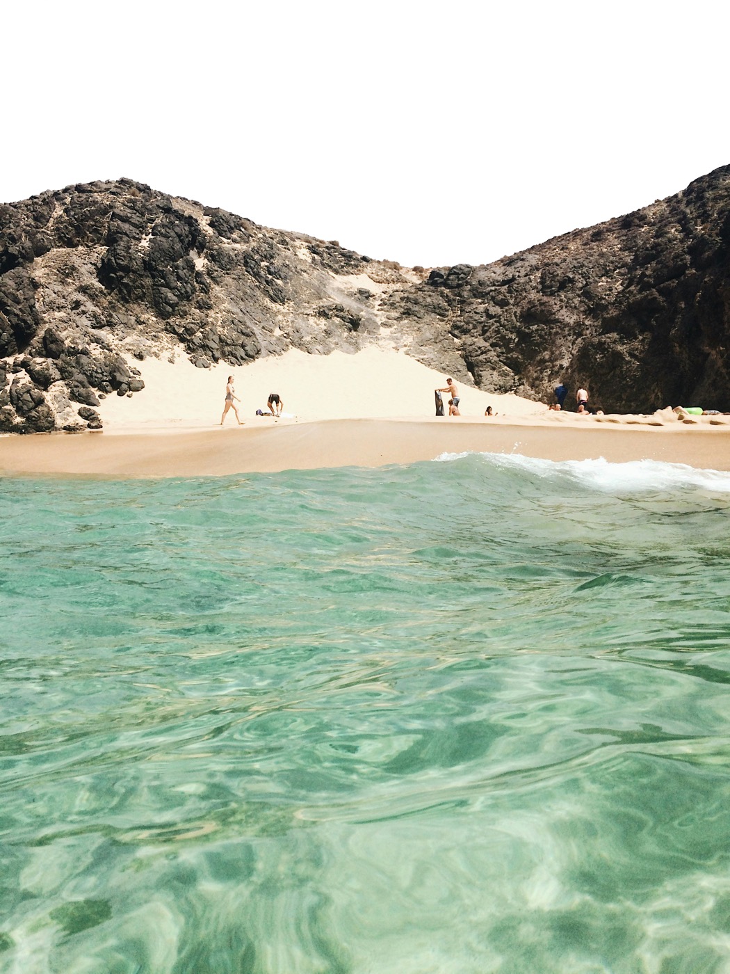 Playa recogida entre rocas volcánicas con el agua de color esmeralda
